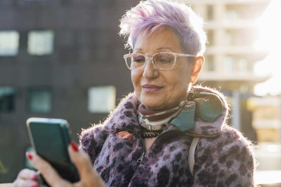 Oudere vrouw met paars haar lacht naar camera. Ervaringsverhaal administratieve dienstverlening